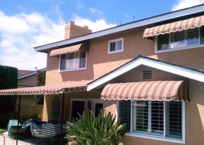 Striped Window Awnings on Two Story House